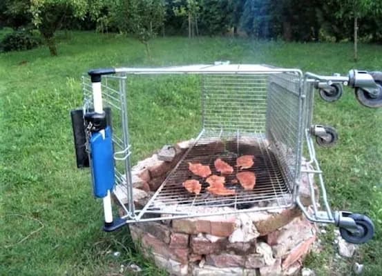 A humorous photo of meat grilling on an improvised barbecue made from a shopping cart basket over a brick fire pit.